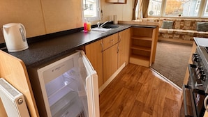 Een compacte keuken met houten kastjes, een inbouwvaatwasser en een fornuis.