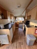 Une cuisine de taille réduite, avec des meubles de rangement en bois, une cuisinière et un évier.