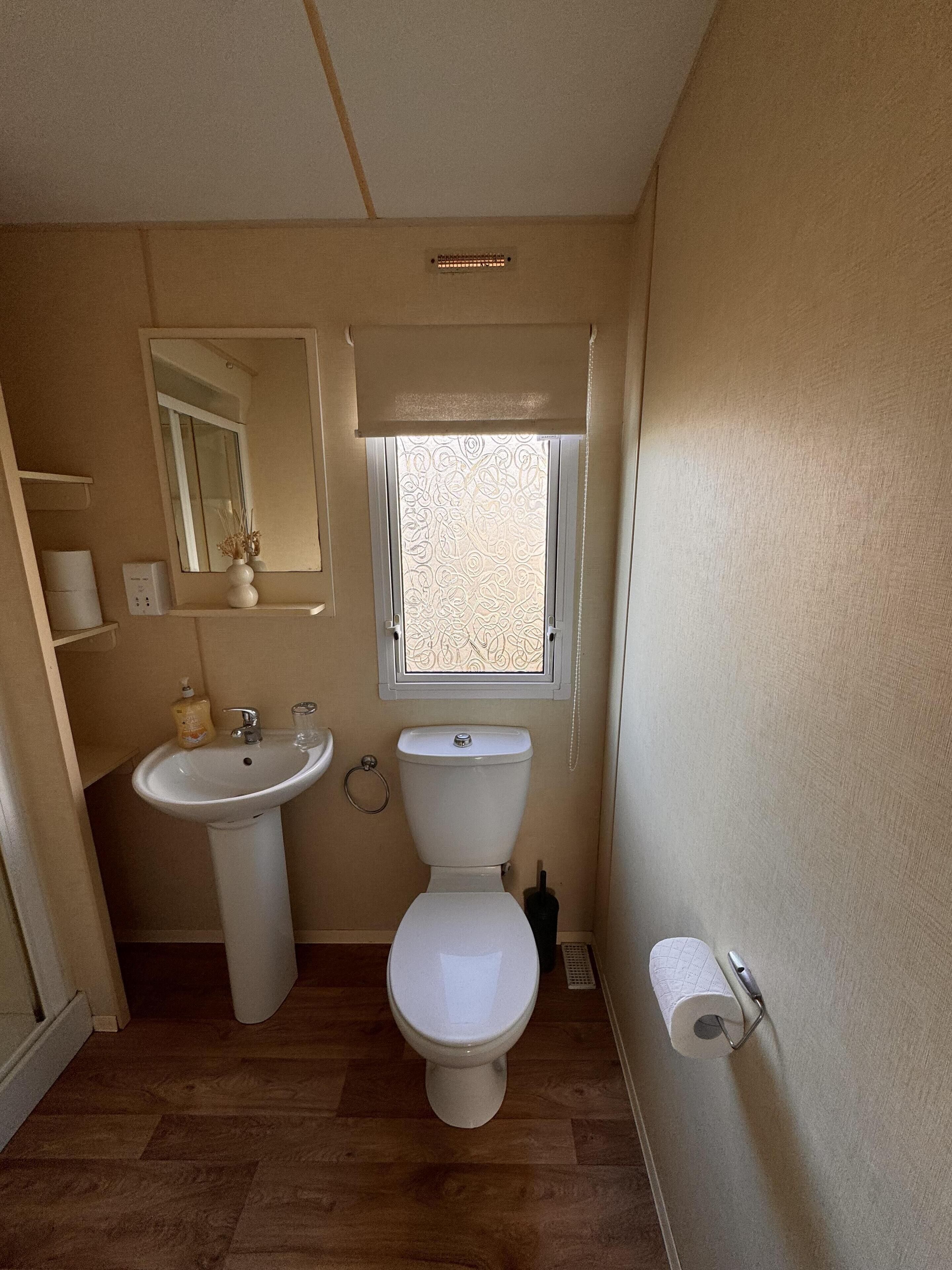 A compact bathroom with a toilet, sink, and window.