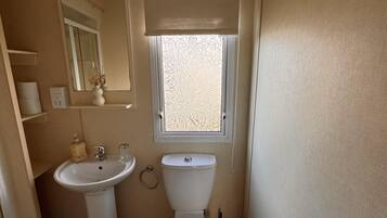 A compact bathroom with a toilet, sink, and window.