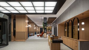 Eine moderne Hotelhalle mit einer zentralen Rezeption, Holzvertäfelung und einer Glaskuppel.