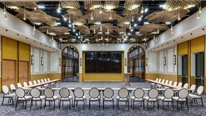 Ein Konferenzraum mit langem Tisch und Stühlen, einem großen Bildschirm und einer Decke mit Pendelleuchten.