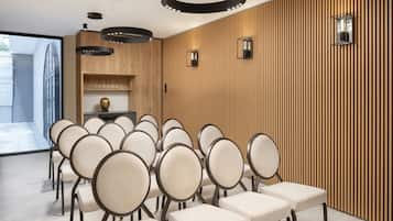 A conference room with rows of chairs, wooden paneling, and pendant lighting.