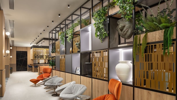Ein modernes Interieur mit einer langen Rezeption, Holzvertäfelung und orangefarbenen und grauen Stühlen.