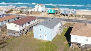 A coastal residential area with houses, a road, and the ocean in the background.