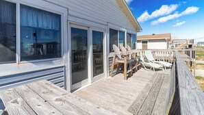 A wooden deck with lounge chairs and a covered area with a table and chairs.