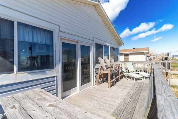 A wooden deck with lounge chairs and a covered area with a table and chairs. - Sun Realty across the street from the beautiful beaches of Kitty Hawk, NC (Kitty Hawk)