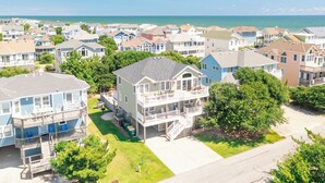 Un quartier résidentiel situé sur la côte, composé de nombreuses maisons à deux étages, dont certaines sont dotées de balcons, et offrant une vue dégagée sur l’océan en arrière-plan.