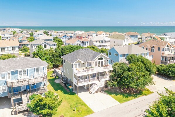 Uma área residencial costeira com várias casas de dois andares, algumas com varandas, e uma vista clara do oceano ao fundo.