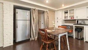 A compact kitchen with a refrigerator, a dining table with chairs, and white cabinets. - Music Room Basement Apartment w/ Private Entrance (Springfield)