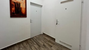Un couloir doté d’un plancher en bois, de murs blancs et de portes numérotées 2 et 3.