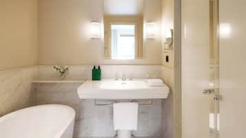 A modern bathroom with a freestanding bathtub, a large sink with a mirror above, and a glass shower enclosure.