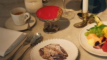 Une table dressée avec une assiette à dessert, une tasse de café, un verre de vin blanc et une assiette de fruits.