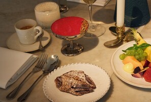 A table set with a dessert plate, a cup of coffee, a glass of white wine, and a fruit plate. - Villa Dahlia (Stockholm)