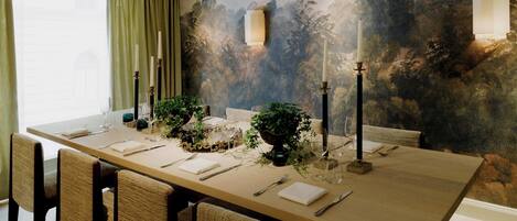 A dining room with a long table set for six, surrounded by chairs.
