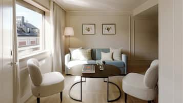 Una sala de estar moderna con un sofá, dos sillones, una mesa de centro y un ventanal con cortinas.