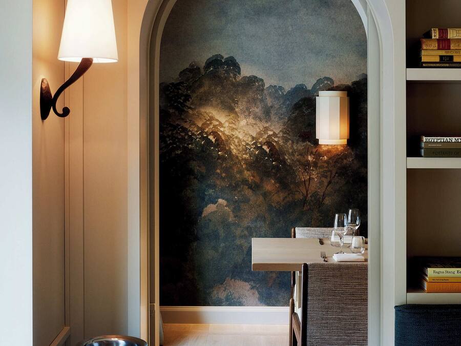 Una habitación con piso de madera, una mesa de comedor con sillas, una estantería y un cuadro en la pared.