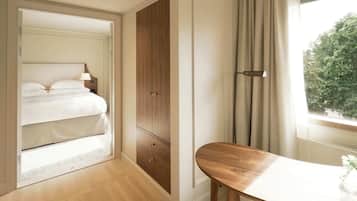 A bedroom with a bed, a wooden wardrobe, a bedside table, and a window with curtains.