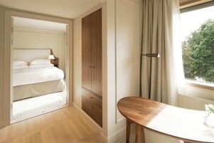 A bedroom with a bed, a wooden wardrobe, a bedside table, and a window with curtains.