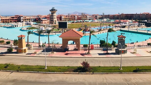 A resort with multiple swimming pools, a central tower, and a large building complex in the background. - Porto sharm elsheikh  (Sharm El Sheikh)