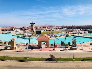 Um resort com várias piscinas, uma torre central e um extenso conjunto de edifícios ao fundo.