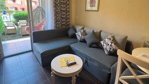 A modern living room with a grey sofa, a small round table with a remote control, and a patterned curtain. - Porto sharm elsheikh  (Sharm El Sheikh)