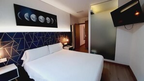 A modern hotel room with a large bed, a geometric-patterned headboard, a wall-mounted TV, and a nightstand with a lamp. - Hostal Laia by gaiarooms (Barcelona)