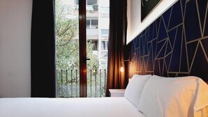 A hotel room with a bed, a view of a balcony, and a geometric-patterned wall. - Hostal Laia by gaiarooms (Barcelona)