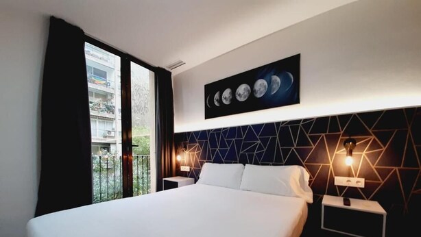 A modern hotel room with a large bed, a geometric-patterned headboard, and a wall-mounted artwork depicting the moon phases. - Hostal Laia by gaiarooms (Barcelona)