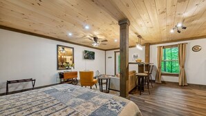 Una habitación amplia con una cama grande, zona de comedor y ventana con cortinas.