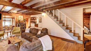 Una sala de estar acogedora con una escalera de madera, sofás de cuero y un comedor con sillas y una mesa.