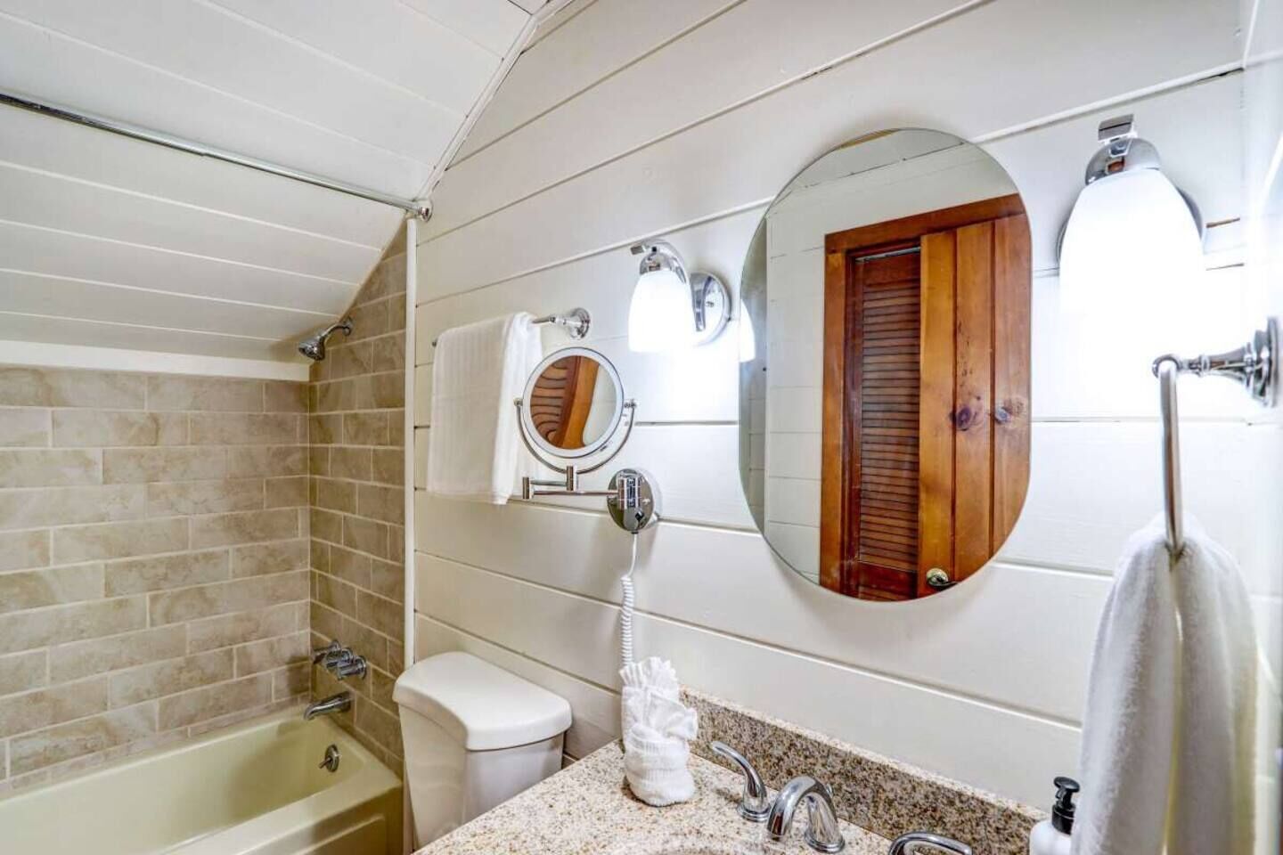 A bathroom with a bathtub, toilet, sink, and two mirrors.