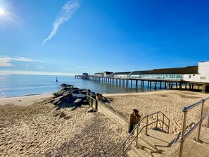 A beach with a wooden jetty extending into the sea, a staircase leading to a building, and a clear sky. - 11 The Craighurst (Reydon)