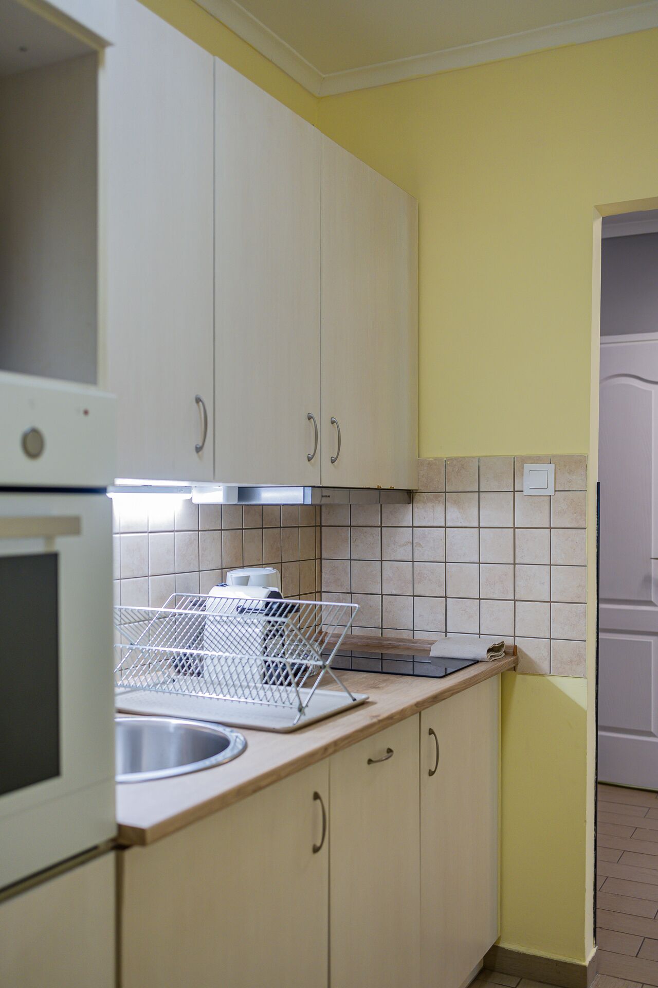 A kitchen with white cabinets, a stainless steel sink, and a tiled backsplash.