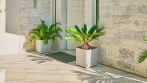 A modern building with a stone facade, a door, and potted plants. - Luxury Villa with Pool,BBQ and Garden Vouliagmeni
 (Voula)