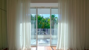 A room with a sliding glass door leading to a balcony with a view of greenery. - Luxury Villa with Pool,BBQ and Garden Vouliagmeni
 (Voula)