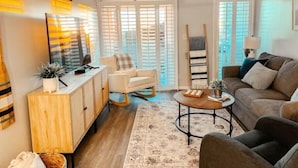 Un soggiorno moderno con divano, tavolino, televisore, mobile e ventola a soffitto.