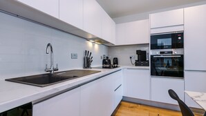 A modern kitchen with white cabinets, a stainless steel sink, and a Bosch oven.