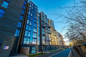 A modern multi-story building with large windows and balconies, a brick facade, and a clear sky. - Charming 1-bed Apartment in Birmingham (Birmingham)