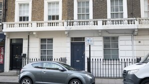 A two-story building with a row of windows on the ground floor and a black door. - Beautiful 1-bed Apartment in London (London)