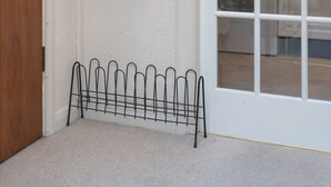 A room with a white door, a coat rack with a black jacket, and a metal rack. - Beautiful 1-bed Apartment in London (London)