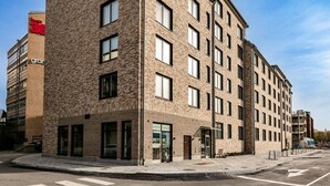 A multi-story building with a brick facade, large windows, and a visible entrance. - Stylish Urban Home in Stockholm (Stockholms län)