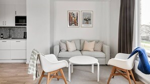 A modern living room with a sofa, two chairs, a coffee table, and a kitchen in the background. - Stylish Urban Home in Stockholm (Stockholms län)