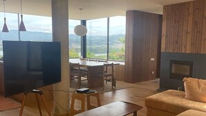 A modern living room with a large TV, wooden furniture, and a view of the outdoors.
