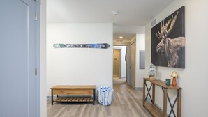 A hallway with a bench, a wall-mounted snowboard, a console table with a lamp, and a moose painting.