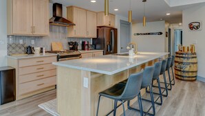 A modern kitchen with wooden cabinets, stainless steel appliances, and a central island with bar stools.