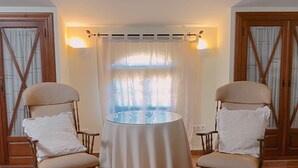 A room with two wooden chairs, a round table, and a window with curtains. - Casa Lares (Casas de Don Pedro)