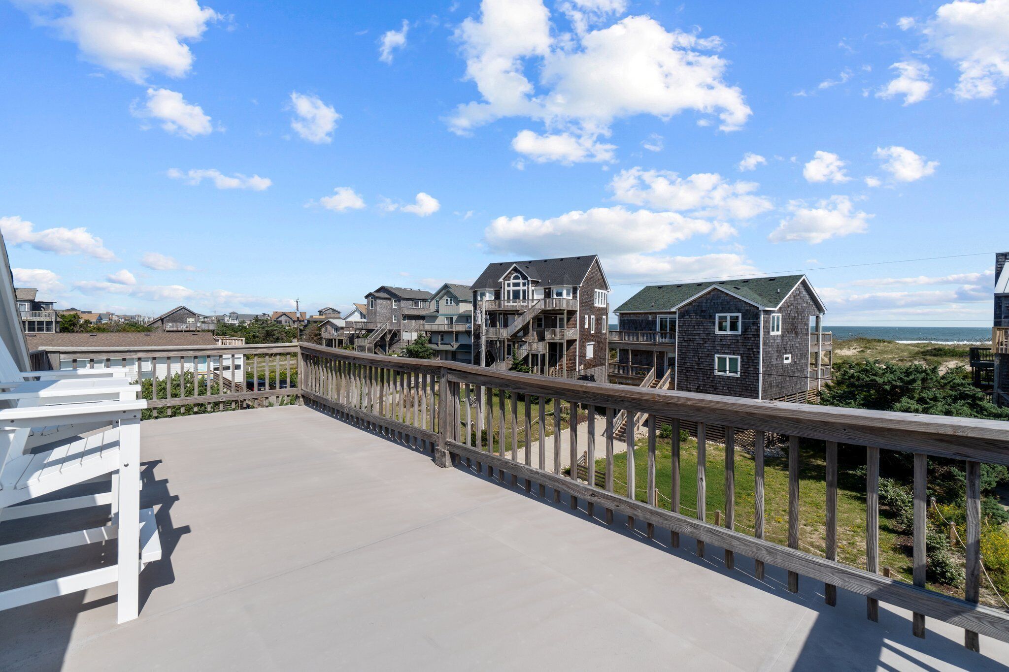 Um bairro residencial com casas, um deck de madeira e vista para o oceano.
