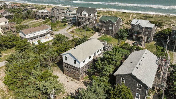 An aerial view of a coastal residential area with houses, a beach, and the ocean in the background. - Ocean View, Semi-Oceanfront, Screened In Porch, Beach Access (Avon)
