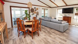 A spacious living area with a dining table, chairs, a grey sofa, and a ceiling fan. - Ocean View, Semi-Oceanfront, Screened In Porch, Beach Access (Avon)